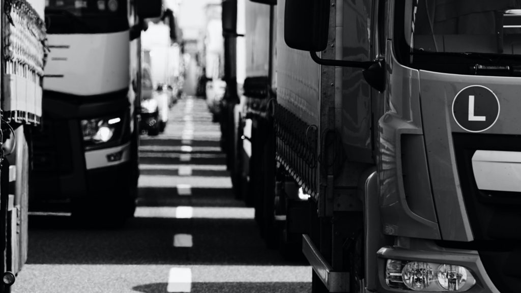 Black and white close-up of lorries on the road.