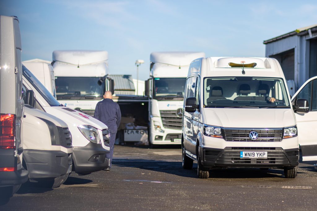 A man walking next to a selection of white refrigerated vehicles.